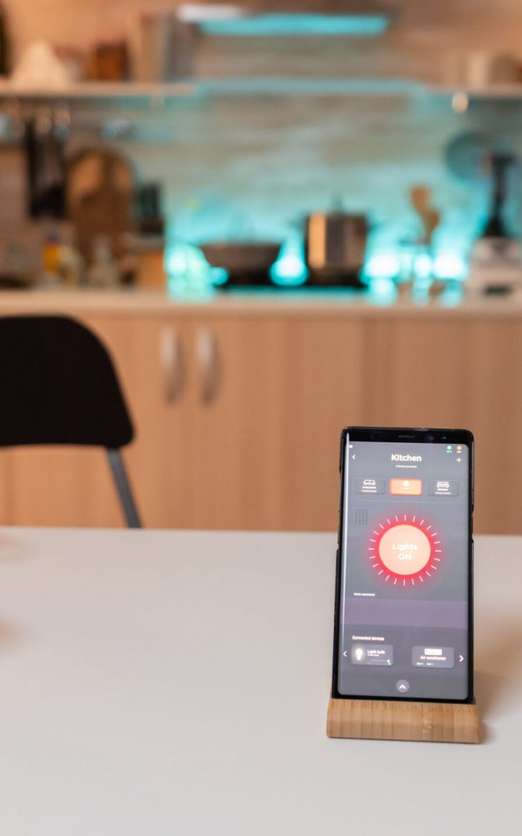 Smartphone with smart home application to turn on and off the lights in the house. Phone with touching screen late at night with technology to change lights in home.